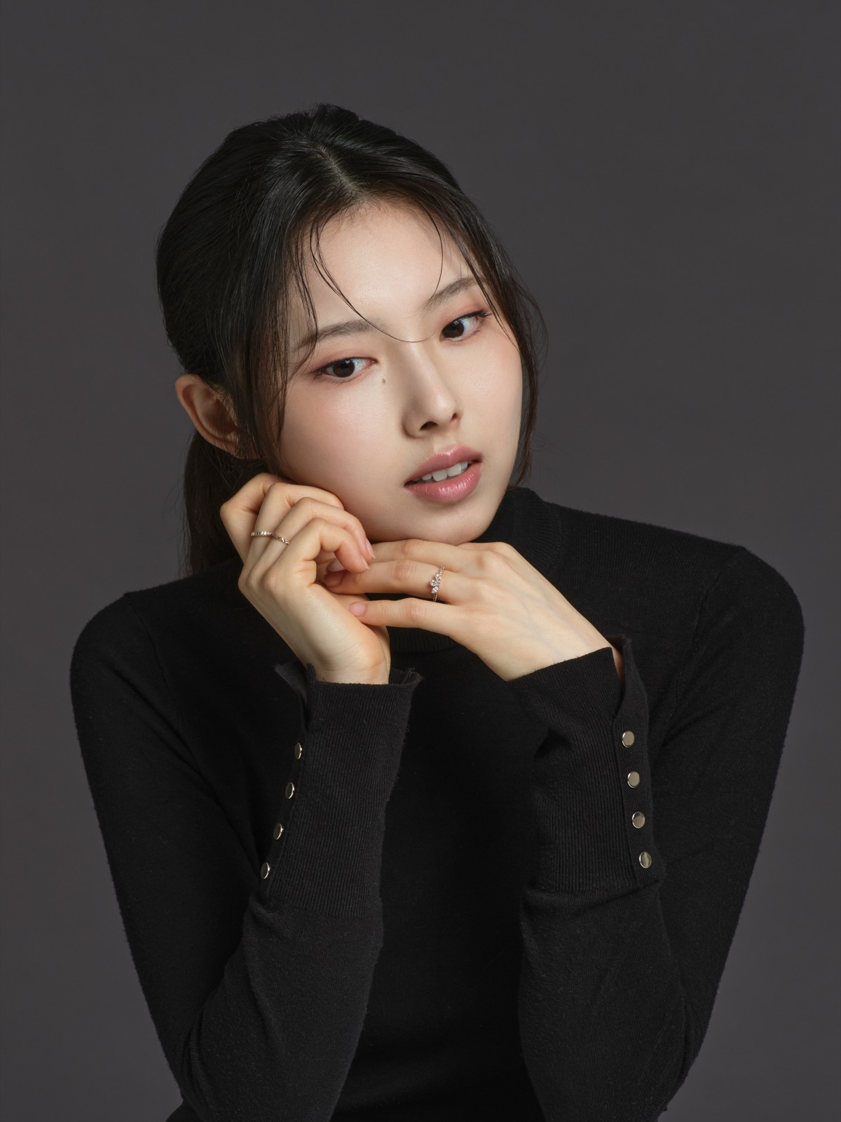 Portrait of Yena Cho in a black knit top against a grey background